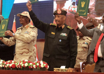 Sudan's Army chief Abdel Fattah al-Burhan (C R) and paramilitary commander Mohamed Hamdan Dagalo (C L) lift documents alongside civilian leaders following the signing of an initial deal aimed at ending a deep crisis caused by last year's military coup, in the capital Khartoum on December 5, 2022. - The past year has seen near-weekly protests and a crackdown that pro-democracy medics say has killed at least 121, a spiralling economic crisis exacerbated by donors slashing funding, and a resurgence of ethnic violence in several remote regions. Divisions among civilian groups have deepened since the coup, with some urging a deal with the military while others insist on "no partnership, no negotiation". (Photo by ASHRAF SHAZLY / AFP)