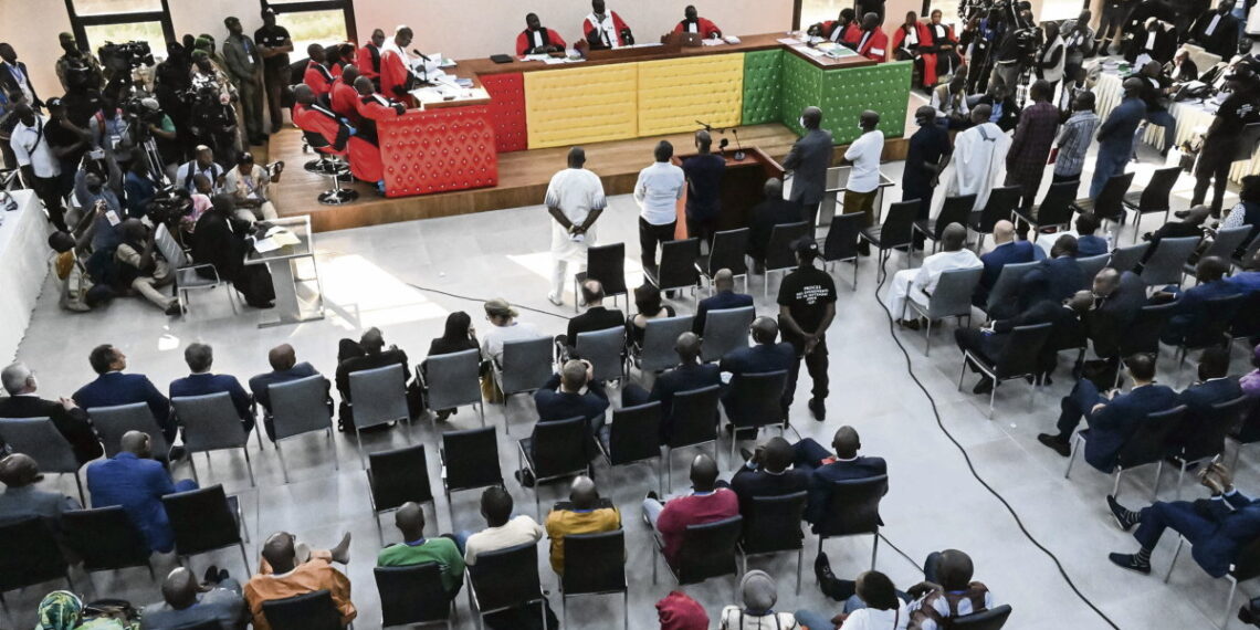 The eleven accused stand as the session starts inside the new courthouse in Conakry on September 28, 2022 during the opening of the trial for the massacre of 156 people in September 2009. - The trial of former Guinean dictator Moussa Dadis Camara and other former officials over the September 28, 2009 stadium massacre opened on September 28, 2022, in the capital Conakry, an AFP correspondent reported. (Photo by CELLOU BINANI / AFP)